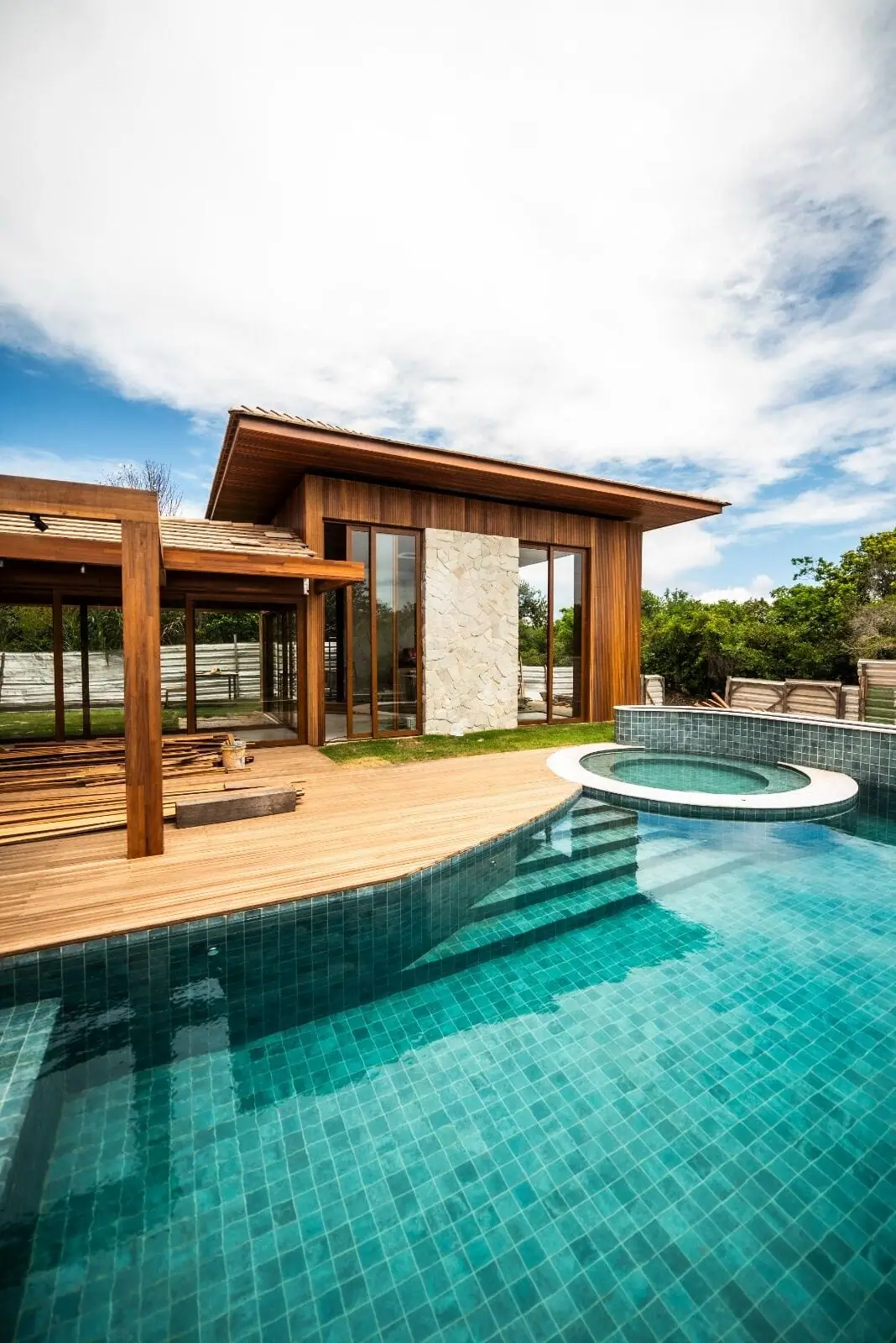 Casa contemporânea com piscina e amplas esquadrias de vidro voltadas para o deck de madeira