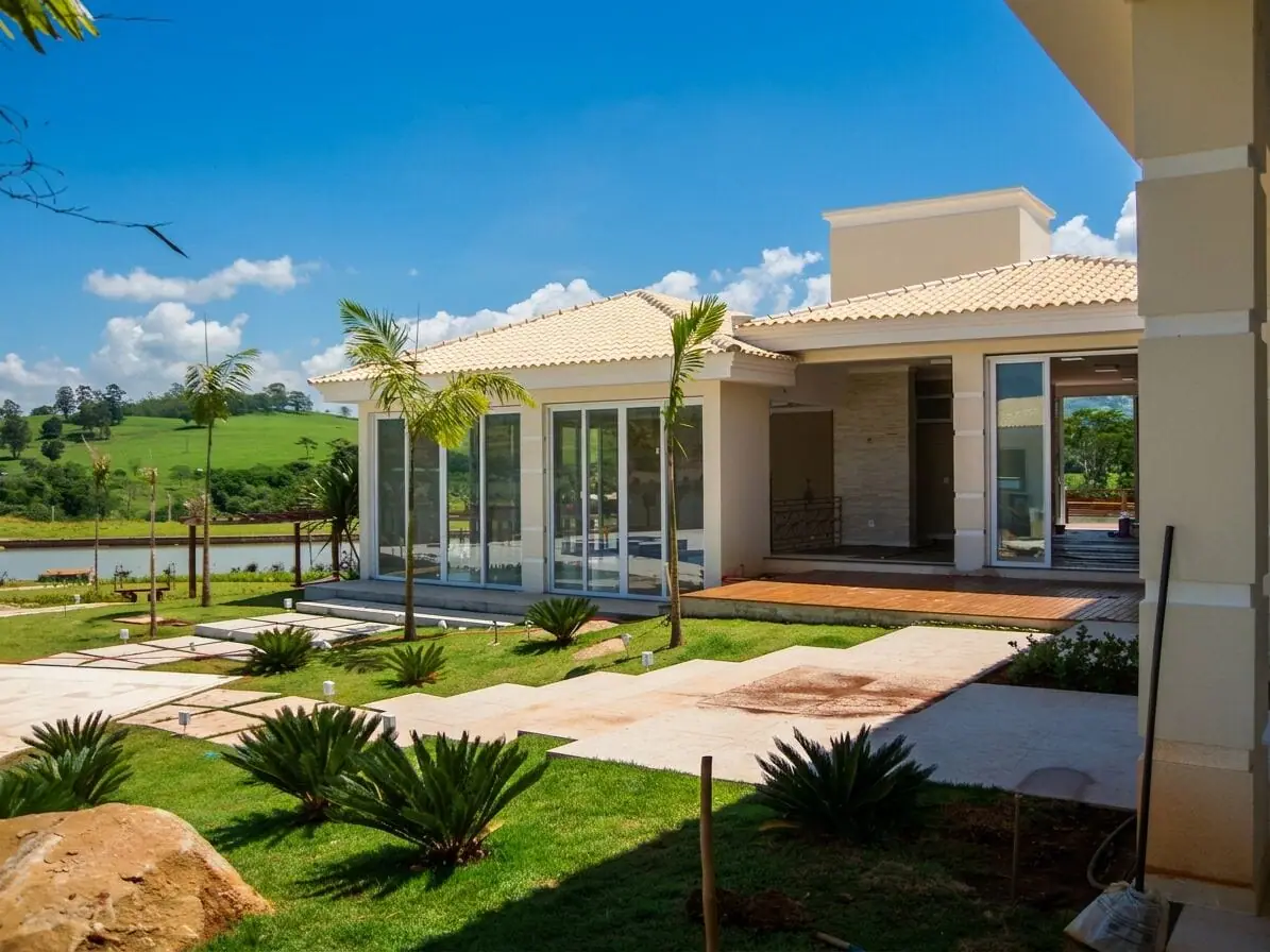 Fachada de casa de campo com grandes esquadrias de vidro e vista para o lago