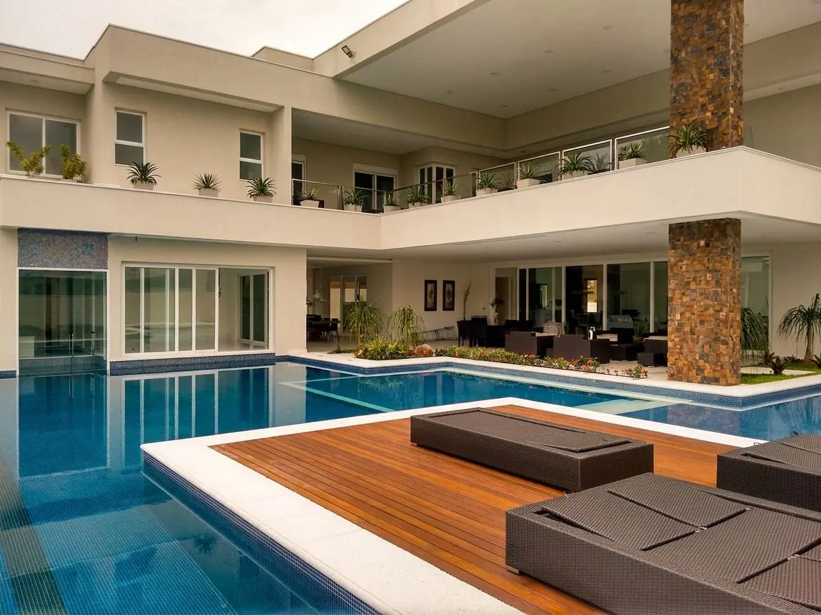 Mansão com pátio interno, piscina e esquadrias deslizantes integrando os ambientes