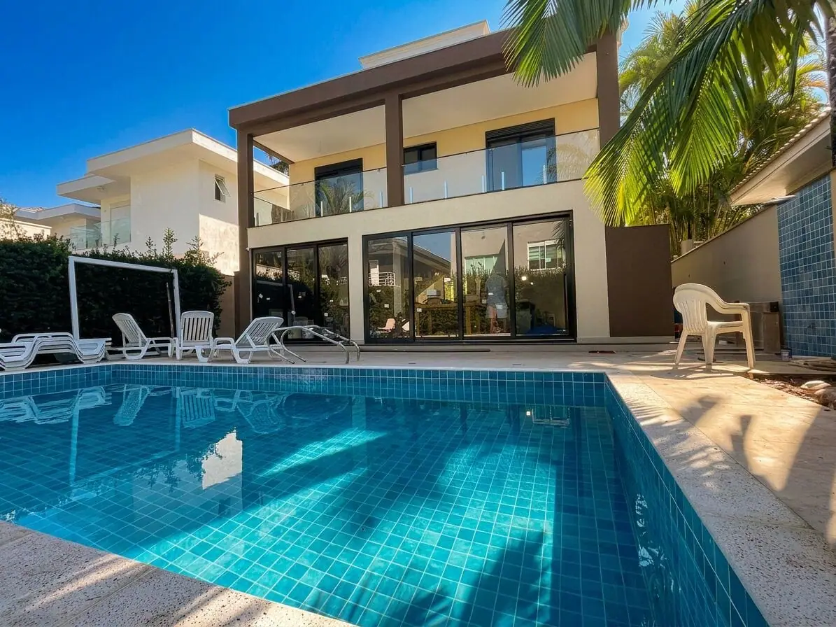 Residência de praia com fachada em vidro e portas de correr para área de piscina